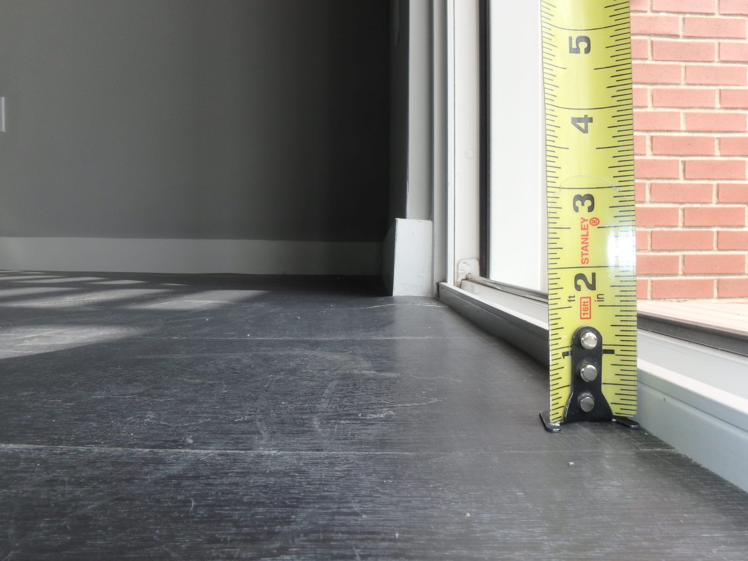 A measuring tape shows a height of 1.5 inches from the top of the interior finished floor to the top of the sliding door track.