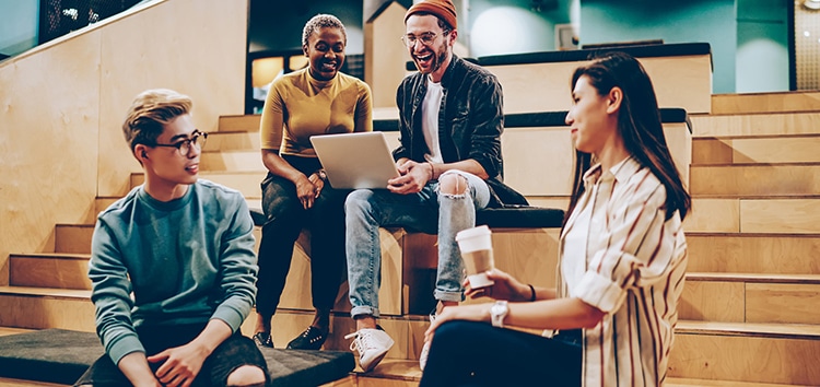 Happy group of male and female multiracial students having fun on meeting for discussion coursework project in modern campus, smiling cheerful colleagues brainstorming and share ideas on meeting