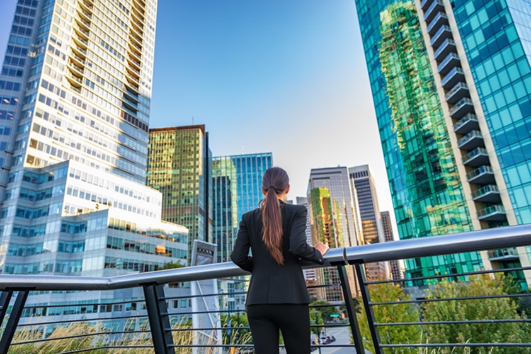 Business woman in city center looking at view of skyline skyscrapers in Vancouver downtown , Canada. Businesswoman from the back pensive thinking about success and future in career and job.